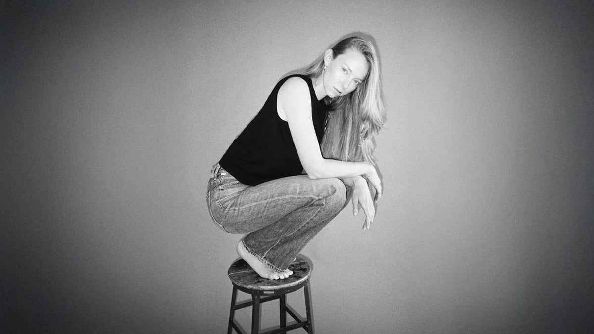 A woman sitting on a table wearing a denim skirt.